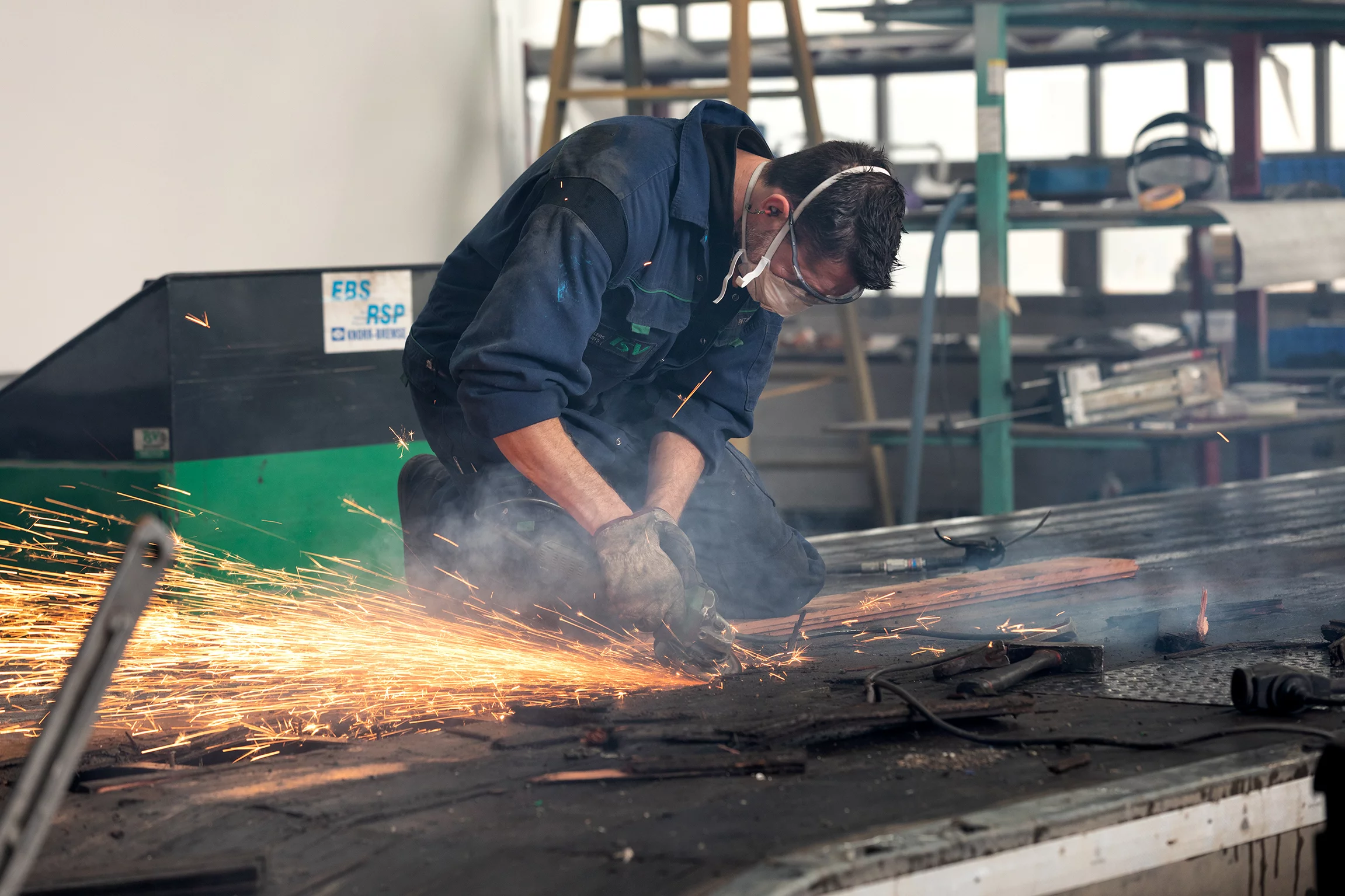 twee mannen aan het werk in een grote garage, ze werken aan een rode truck. Ze zijn in overleg