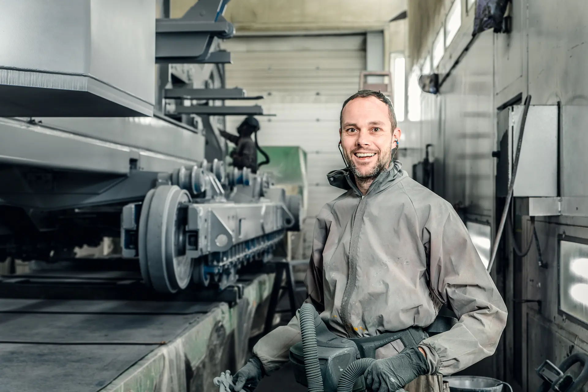 Een spuiter in een beschermend pak bezig met het bespuiten van een truck